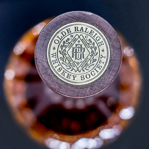 whiskey society coin on top of olde raleigh bourbon bottle